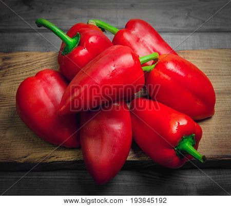 Heap Fresh red Bulgarian pepper on a gray rustic wooden background. Cutting board for red bell pepper.