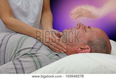 Spiritual help during a healing session - female hands laid either side of a male patient's throat channeling energy together with the help of a higher power on a dark purple background