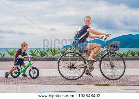 Happy Family Is Riding Bikes Outdoors And Smiling. Mom On A Bike And Son On A Balancebike