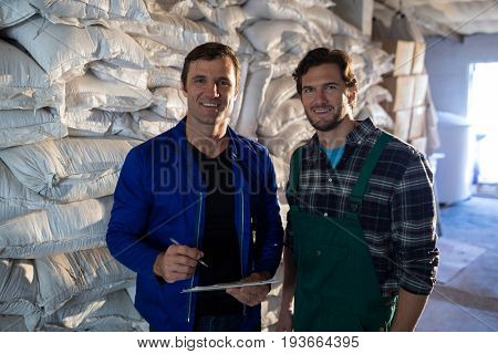 Portrait of coworkers standing by barley scaks at factory