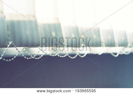 Vertical window blinds with sun light as a background.