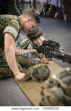 Ship Tour USS Kearsarge (LHD 3) Wasp-class amphibious assault ship: US Navy personnel helps unidentified boy take aim through rifle scope on M240B medium machine gun. Fleet Week NEW YORK MAY 25 2017.