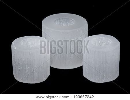 White selenite cylinder tea light holders on black background