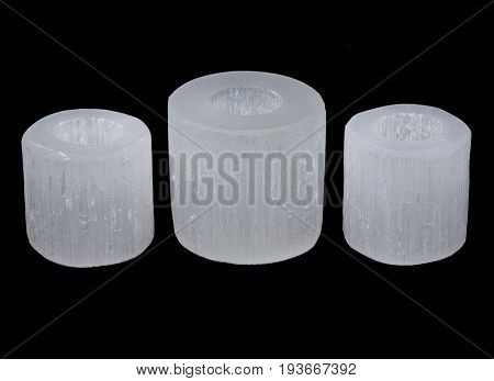 White selenite cylinder tea light holders on black background