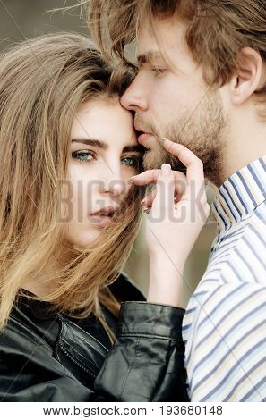 Young couple of sensual lovers outdoors. Sexy woman and cute girl with stylish makeup and long hair and handsome caucasian man touching each other with love and tenderness