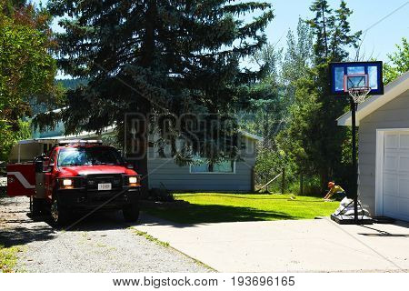 KALISPELL, MONTANA, USA - June 21, 2017: Firefighter rolling up hose in the front yard of a home threatened by a contained grass fire