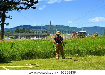 KALISPELL, MONTANA, USA - June 21, 2017: Firefighter rolling up hose in the front yard of a home threatened by a contained grass fire