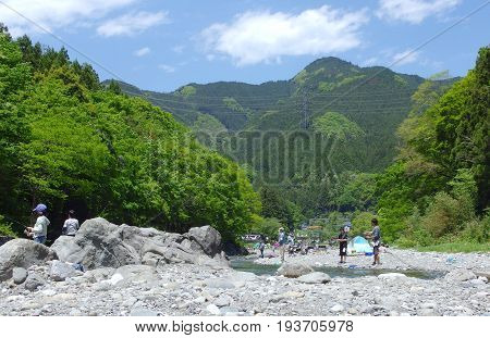 2016 May 5. TAMAKAWA TOKYO JAPAN. People are fishing at TAMAKAWA river that surrounded by green forest and natural MITAKE mountain