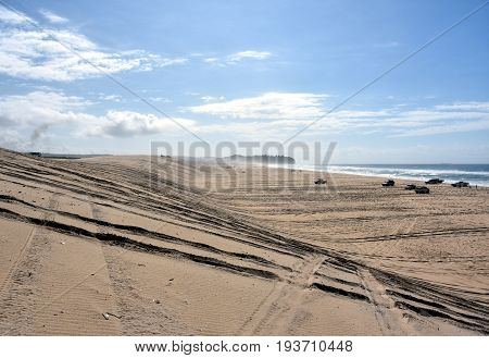 Horizontal landscape of the beach with cars. 4wd cars at Crokers creek (Belmont - Nine Miles - Beach NSW Australia). Redhead Point in the background.