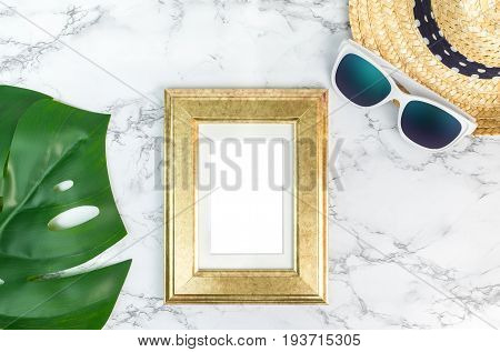 Blank Vintage Golden Color Picture Frame On Green Monstera Leaf With Sunglasses And Straw Hat On Whi