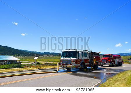 KALISPELL, MONTANA, USA - June 21, 2017: Firefighter working the hose on a fire truck at grass fire scene