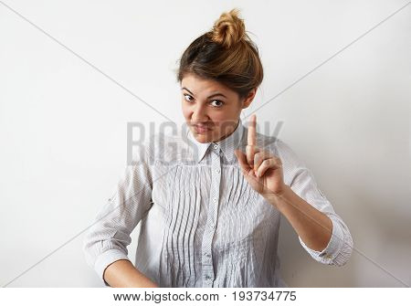 Funny young Caucasian woman with hair bun wagging her index finger as if warning someone or saying: Attention please or Listen to me. Human emotions life perception feelings reaction and attitude
