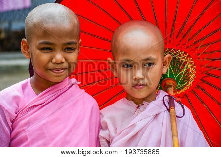 DAWEI MYANMAR - JULY 11 2015: Nuns in pink robes with red paper umbrella in Buddhist temple in Dawei of Myanmar.