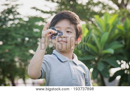Chld  Playing  Fidget Spinner On Nature Background