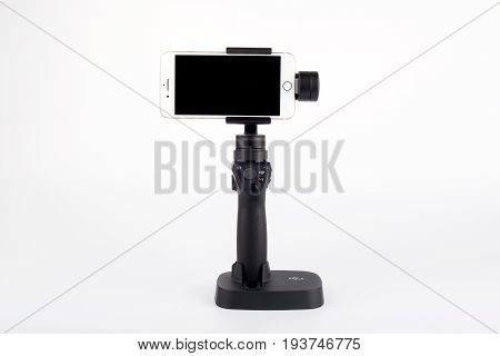 Riga, Latvia - July 3, 2017: New DJI Osmo Mobile gimbal stand for smartphone with Golden iPhone 7 Plus. The DJI Osmo hardware and mobile app allows smooth video shooting. 4k, Ultra HD