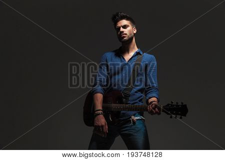 dramatic guitarist standing on grey background