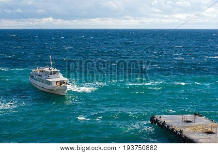 Pleasure boat is mooring to a small pier on a Black Sea shore Crimea Ukraine.