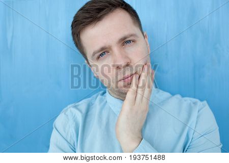 Caucasian thoughtful young man standing by the blue woodenwall. Think about life