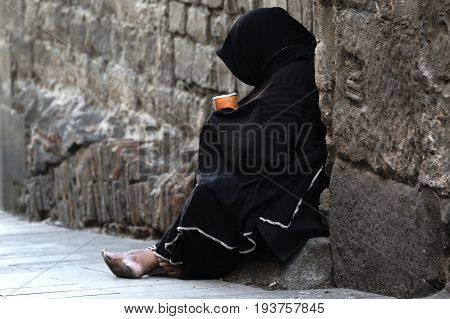 Poor woman begging sitting in the street. Empty copy space for Editor's text.