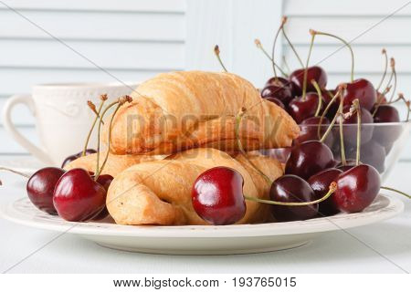 Fresh croissant with cherries in glass bowl