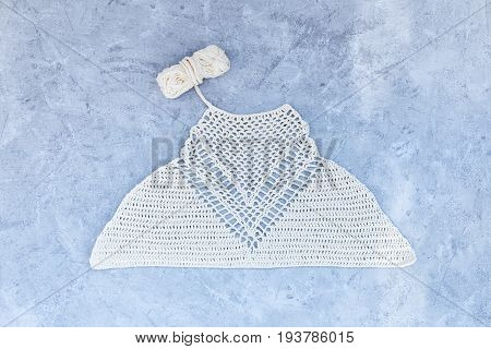 White crocheted crop top made of cotton on a blye background