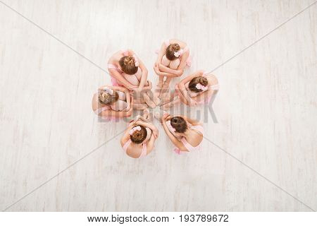 Little ballerinas dancing ballet in studio. top view. Group of girls practicing position sitting on floor, classical dance studio
