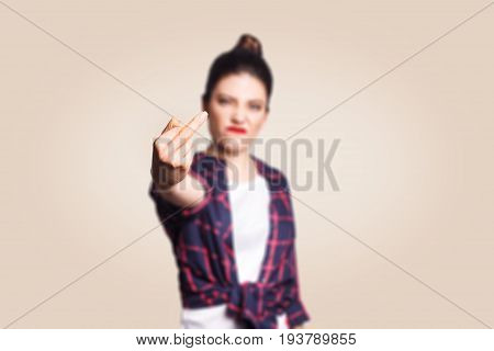 Middle finger sign. Unhappy angry young woman showing middle finger with unsatisfied face. studio shot on beige background. focus on fingers.