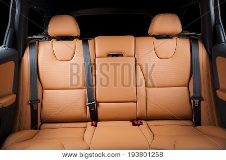 Back passenger seats in modern luxury car, frontal view, red orange sand leather