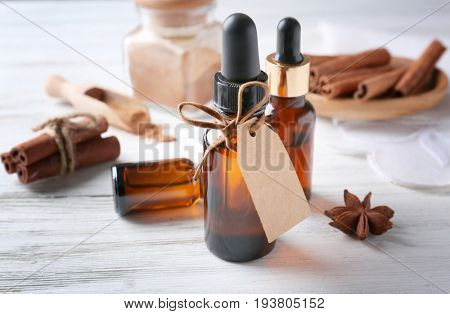 Bottles of cinnamon oil on wooden background