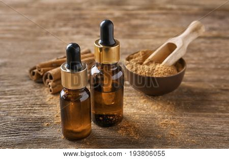 Bottles of cinnamon oil on wooden background