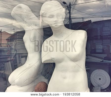 Two plaster statues shot through shop window