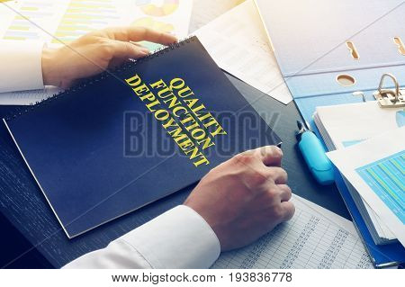 Manager takes book QFD - Quality Function Deployment.