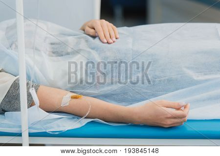 Pensive woman transfused lying in hospital ward.