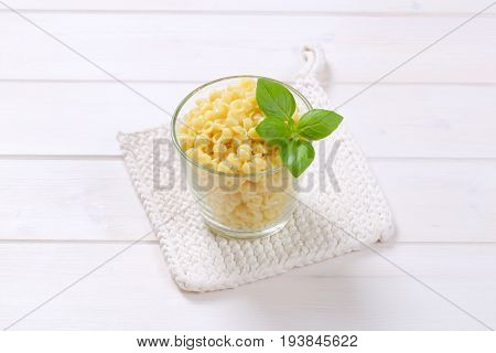 glass of small pasta shells on white table mat