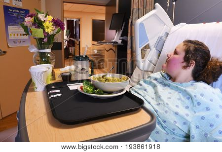 KALISPELL, MONTANA, USA - June 19, 2017: Patient lies in bed with a bowl of hospital food on her tray