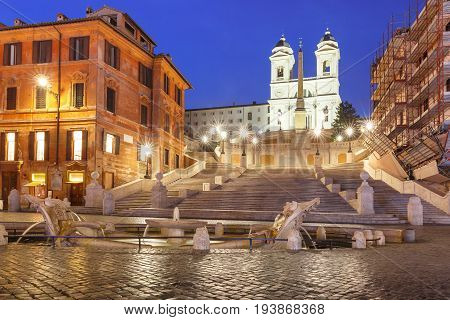 Monumental stairway Spanish Steps, seen from Piazza di Spagna, and the Early Baroque fountain called Fontana della Barcaccia or Fountain of the ugly Boat during morning blue hour, Rome, Italy.