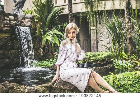 Woman is posing in a tropical garden of Bali island.