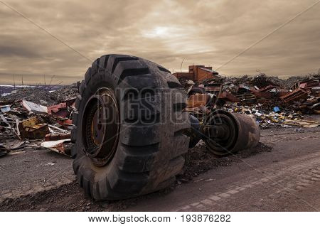 huge wheel from a truck on a dirt road in the middle of a garbage dump part of a rear axle