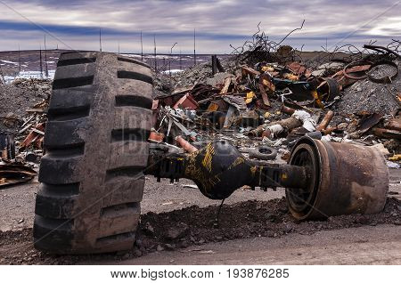 huge wheel from a truck on a dirt road in the middle of a garbage dump part of a rear axle