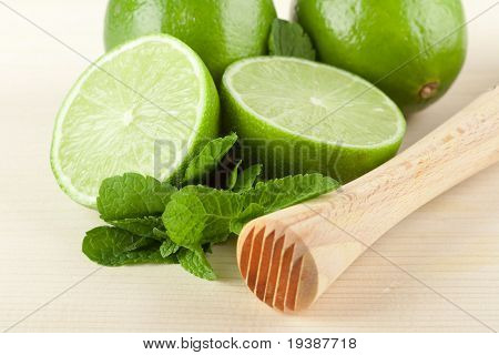 Mojito mix na dřevěné tabulce: limetky, máta a Muddler-drtič