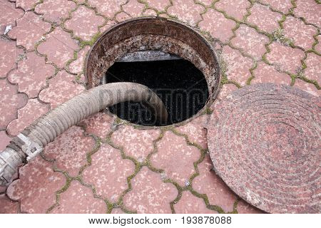 man pumping sewage from the drain hole.