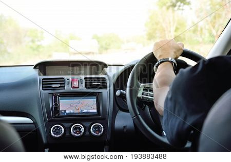 Asian man driving a car with navigation device for traveling. Close up of hand of people and gps tuchscreen focus on GPS LCD Copy space.