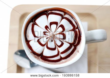 Top view of cup of hot chocolate with foam in the form of flower isolated on wood plate