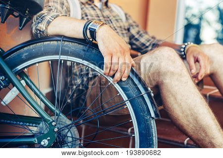 Closeup young guy hand lies on a bicycle wheel