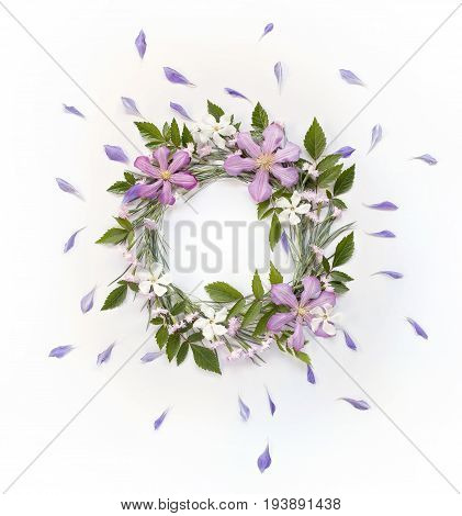 Frame wreath with white and pink flowers branches leaves and petals and big purple flowers of Clematis. Flat lay overhead view.
