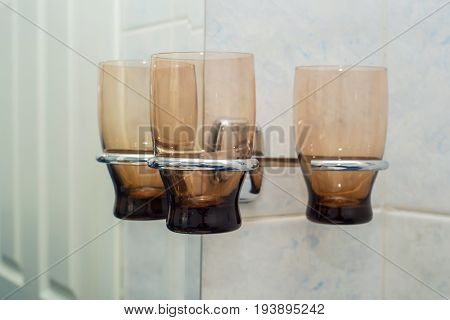 Close up set of empty glasses hanging on tap in bathroom