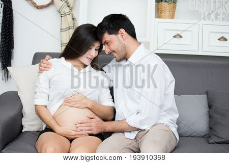 Asian Pregnant Woman And Husband With Happy Emotion Together At Home.