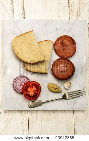 grilled scalded sausage with tomato purple onion garlic bread and mustard on a marble plate