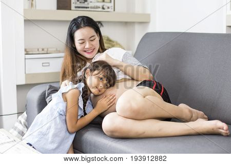 Happy Child Listen To Belly Of Pregnant Woman. Family Having Fun Indoor. Mothers Day Concept