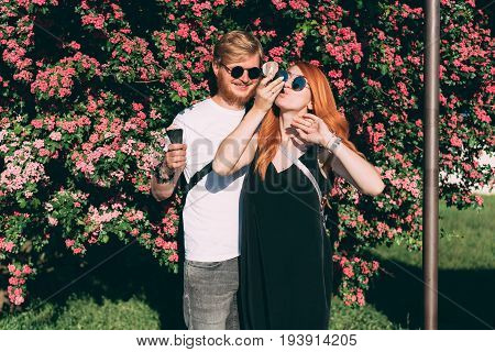 Couple in park eating ice cream cones, posing on camera